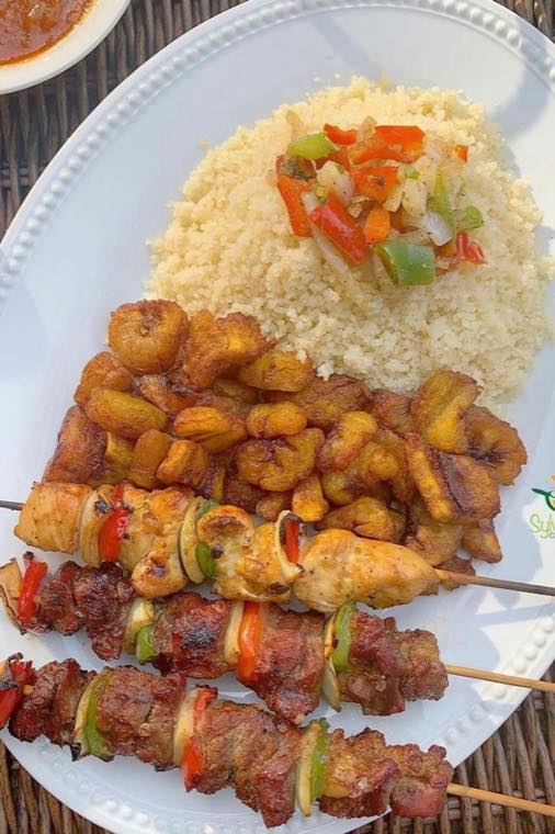 Assiette d'alloco, bananes plantain dorées, avec brochettes de poulet et riz